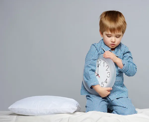 Liten pojke i blå pyjamas med klocka — Stockfoto