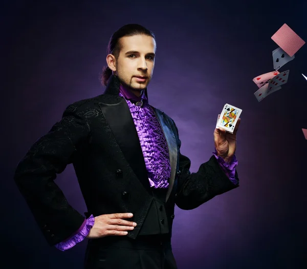 Young brunette magician in stage costume showing card tricks — Stock Photo, Image