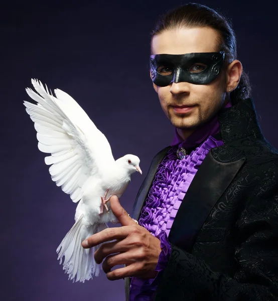 Young handsome brunette magician man in stage costume with his trained white doves — Stock Photo, Image