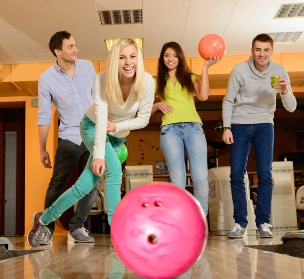 Grupp fyra unga leende människor spelar bowling — Stockfoto