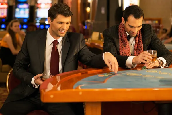 Deux jeunes hommes bien habillés derrière une table de jeu dans un casino — Photo