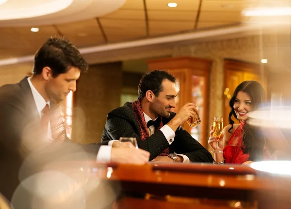 Glückliche junge Leute hinter Spieltisch mit Getränken — Stockfoto