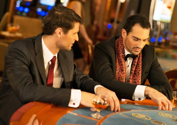 Deux jeunes hommes bien habillés derrière une table de jeu dans un casino — Photo