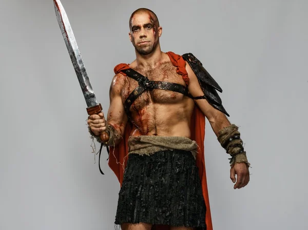 Wounded gladiator with sword covered in blood isolated on grey — Stock Photo, Image