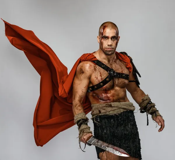 Verwundeter Gladiator mit blutüberströmtem Schwert isoliert auf grau — Stockfoto