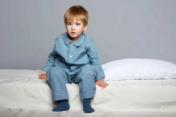 Menino vestindo pijama azul na cama — Fotografia de Stock