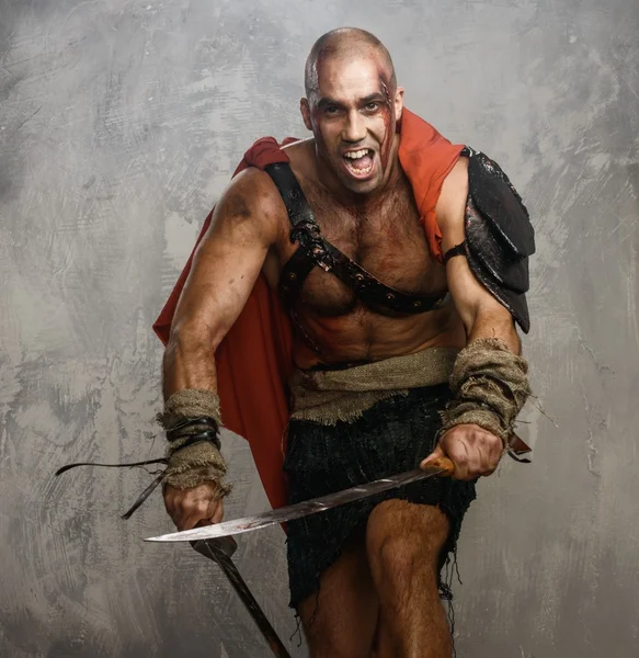 Wounded gladiator with two swords covered in blood — Stock Photo, Image