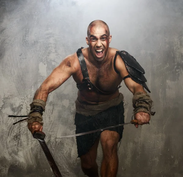 Wounded gladiator with two swords covered in blood — Stock Photo, Image