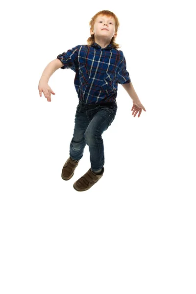 Маленький забавный рыжий мальчик в футболке и джинсах прыгает — стоковое фото