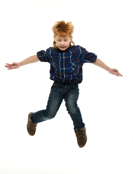 Little funny redhead boy in shirt and jeans jumping — Stock Photo, Image