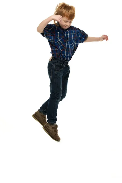 Маленький смішний рудий хлопчик в сорочці і джинсах стрибає — стокове фото