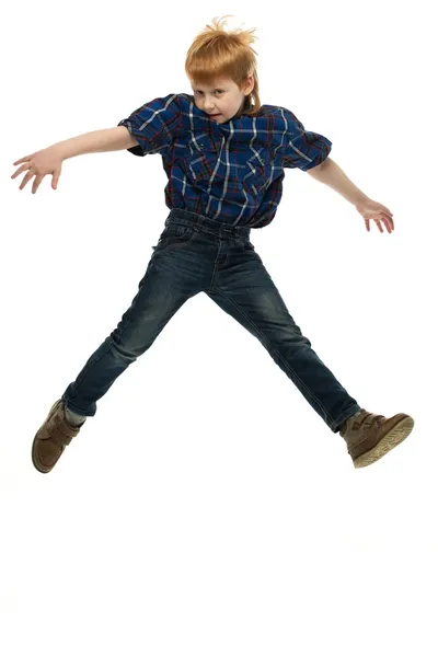 Pequeno menino ruivo engraçado na camisa e jeans saltando — Fotografia de Stock