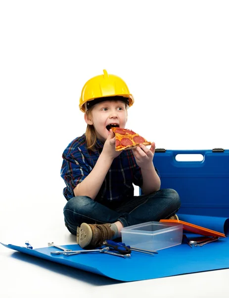 Little funny mechanic boy eating pizza among tools — Stock Photo, Image