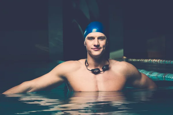 Svalnatý mladý muž v modré čepici v bazénu — Stock fotografie