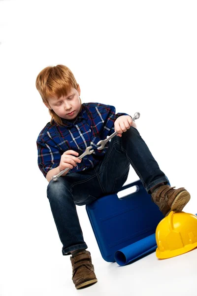 Aburrido niño mecánico con herramientas de llave inglesa sentado en una caja de herramientas —  Fotos de Stock