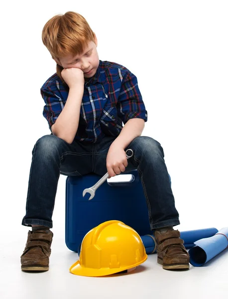 Aburrido niño mecánico con herramientas de llave inglesa sentado en una caja de herramientas — Foto de Stock