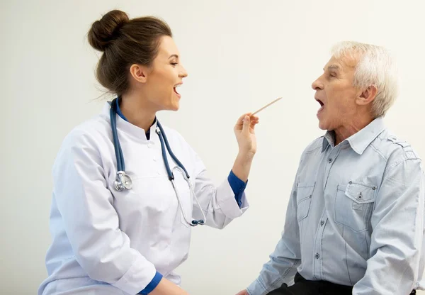 Senior man at doctors's office appointment checking throat — Stock Photo, Image