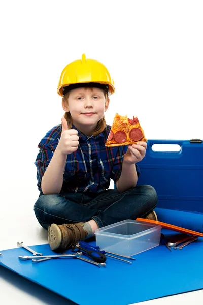 Pouco engraçado mecânico menino comer pizza entre as ferramentas — Fotografia de Stock