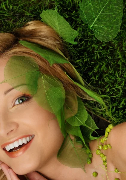 Smiling young woman lying on a fresh spring grass Stock Picture