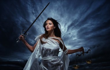 Femida, Goddess of Justice, with scales and sword against dramatic stormy sky clipart