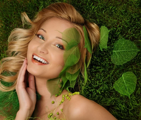 Mujer joven sonriente acostada en una hierba fresca de primavera — Foto de Stock