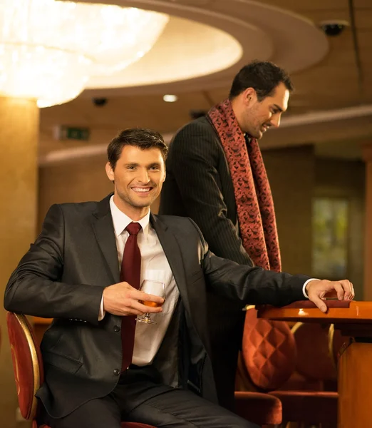 Deux jeunes hommes en costume derrière une table de jeu dans un casino — Photo