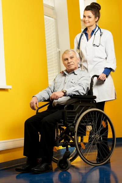 Cheerful young nurse woman with senior man in wheelchair — Stock Photo, Image