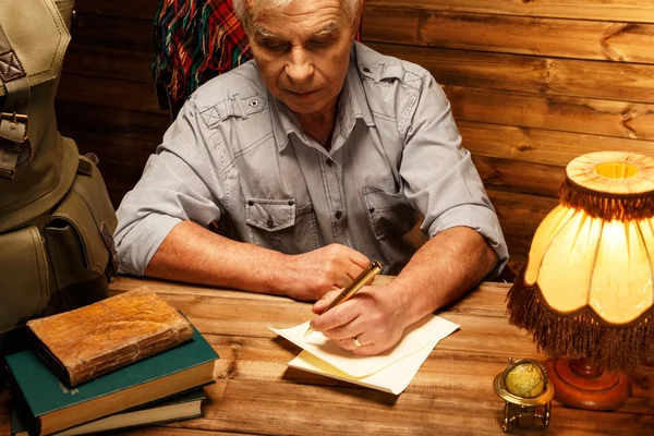 Carta de escrita sênior com caneta pena em interior de madeira caseira — Fotografia de Stock
