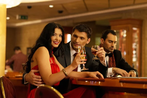 Glada unga människor bakom gambling bord med drycker — Stockfoto