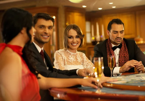 Groupe de jeunes heureux derrière la table de jeu avec des boissons — Photo