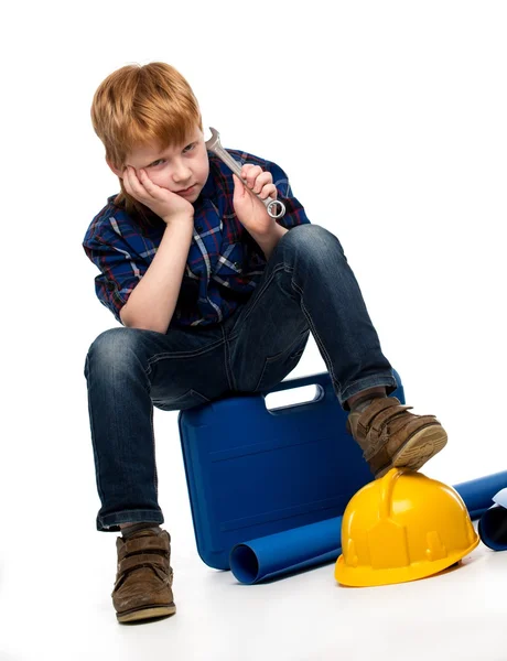 Aburrido niño mecánico con herramientas de llave inglesa sentado en una caja de herramientas — Foto de Stock