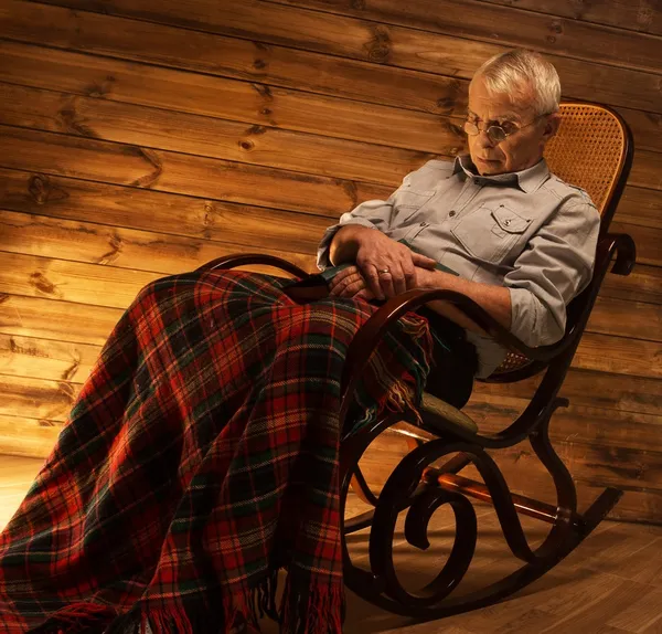 Senior man viel in slaap op schommelstoel in huiselijke houten interieur — Stockfoto