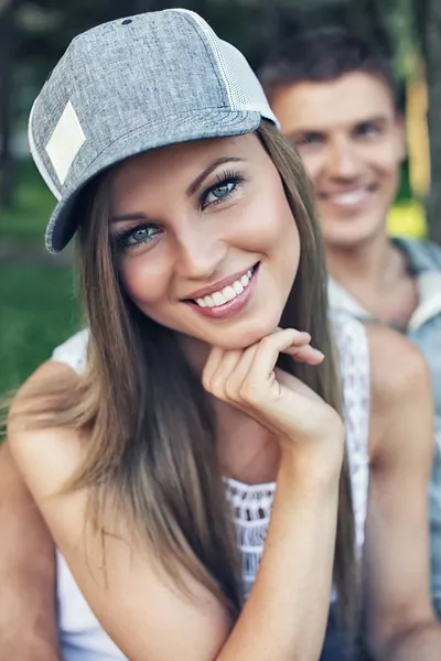 Junges fröhlich lächelndes sportliches Paar sitzt auf Bank im Park — Stockfoto