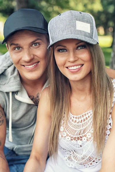 Jovem feliz sorrindo casal desportivo sentado no banco em um parque — Fotografia de Stock