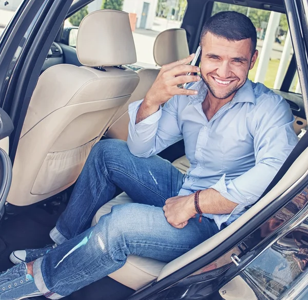 Hombre guapo y elegante en un asiento trasero con un teléfono móvil — Foto de Stock