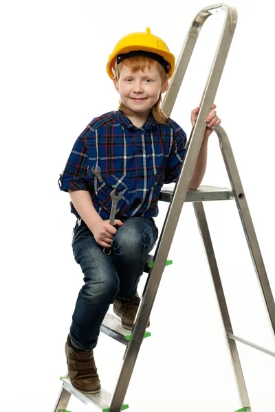 Μικρό αγόρι στο προστατευτικό κράνος με γαλλικό κλειδί εργαλείο σε μια σκάλα — Φωτογραφία Αρχείου
