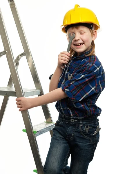 Menino em capacete protetor com ferramenta chave em uma escada — Fotografia de Stock