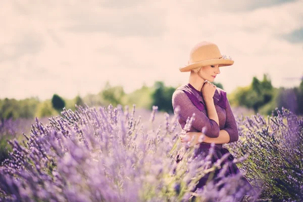 Kvinna i lila klänning och hatt i lavendel fält — Stockfoto