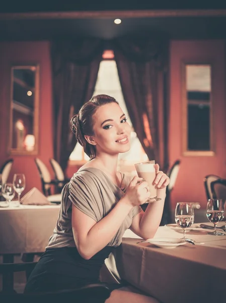 Vacker ung kvinna med fika ensam i en restaurang — Stockfoto