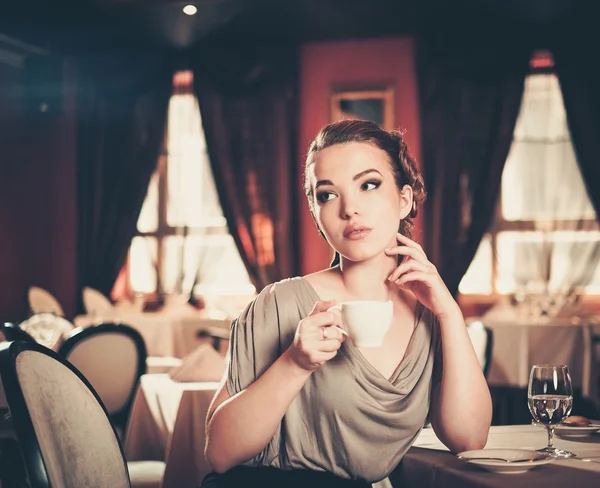 Mulher bonita com xícara de café sozinha em um restaurante — Fotografia de Stock