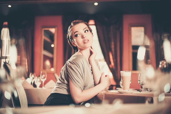 Hermosa joven con una taza de café sola en un restaurante — Foto de Stock