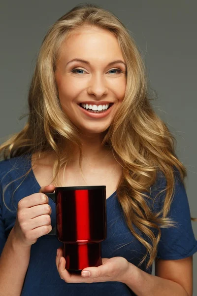 Mujer joven positiva con pelo largo y ojos azules sosteniendo taza termo — Foto de Stock