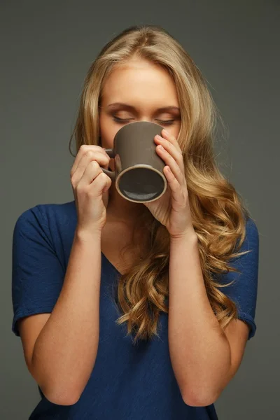 Positive young woman with long hair and blue eyes holding cup — Stock Photo, Image