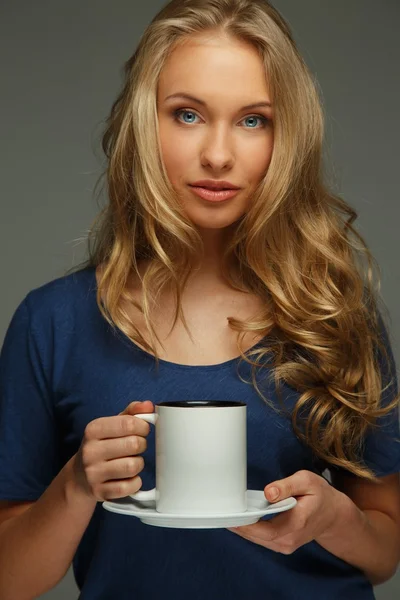 Mujer joven positiva con cabello largo y ojos azules sosteniendo la taza — Foto de Stock