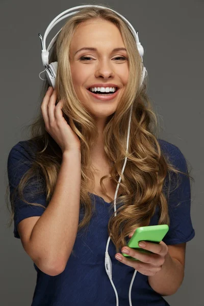 Positive junge Frau mit langen Haaren und blauen Augen hört Musik — Stockfoto