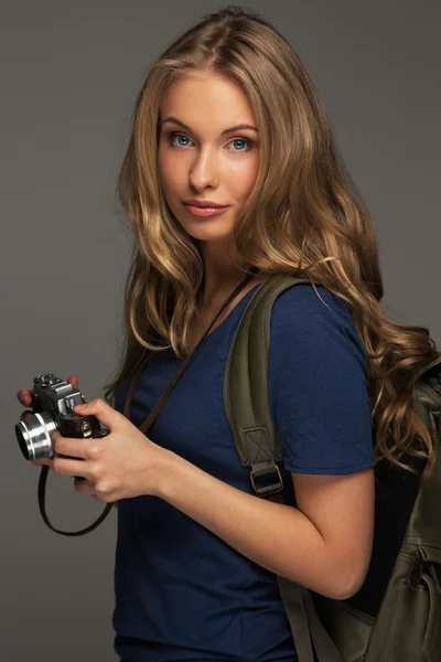 Позитивна молода жінка з довгим волоссям і блакитними очима тримає старовинну камеру в стилі — стокове фото