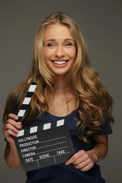 Mujer joven con pelo largo y ojos azules sosteniendo tablero de aplausos de cine —  Fotos de Stock