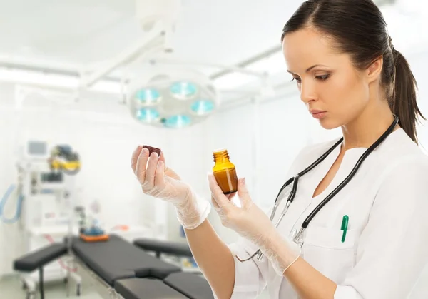 Mujer doctora joven leyendo la prescripción en un vial en el interior de la cirugía —  Fotos de Stock