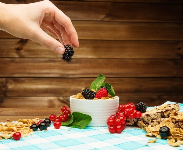 Menschenhand dekoriert Müsli in Schüssel mit frischen Beeren — Stockfoto