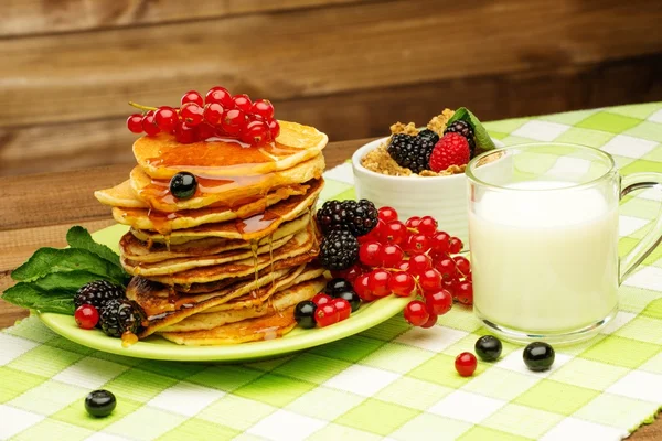 Healthy breakfast with pancakes, fresh berries and milk on tablecloth in rural interior — Stock Photo, Image